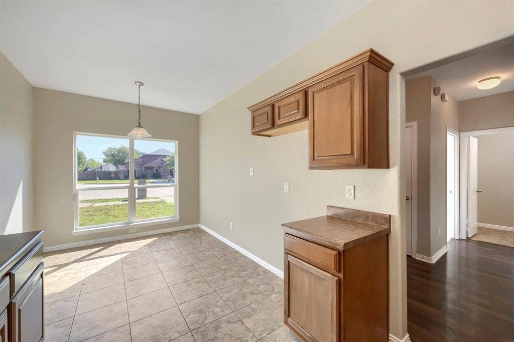 Tiled flooring, overhead lighting, wood-finish cabinetry, and a large window