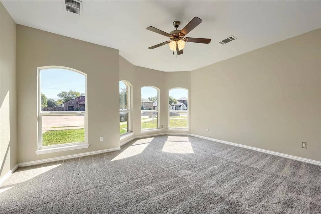 Arched windows, recessed ceiling, ceiling fan with integrated lighting, and neutral-toned carpet