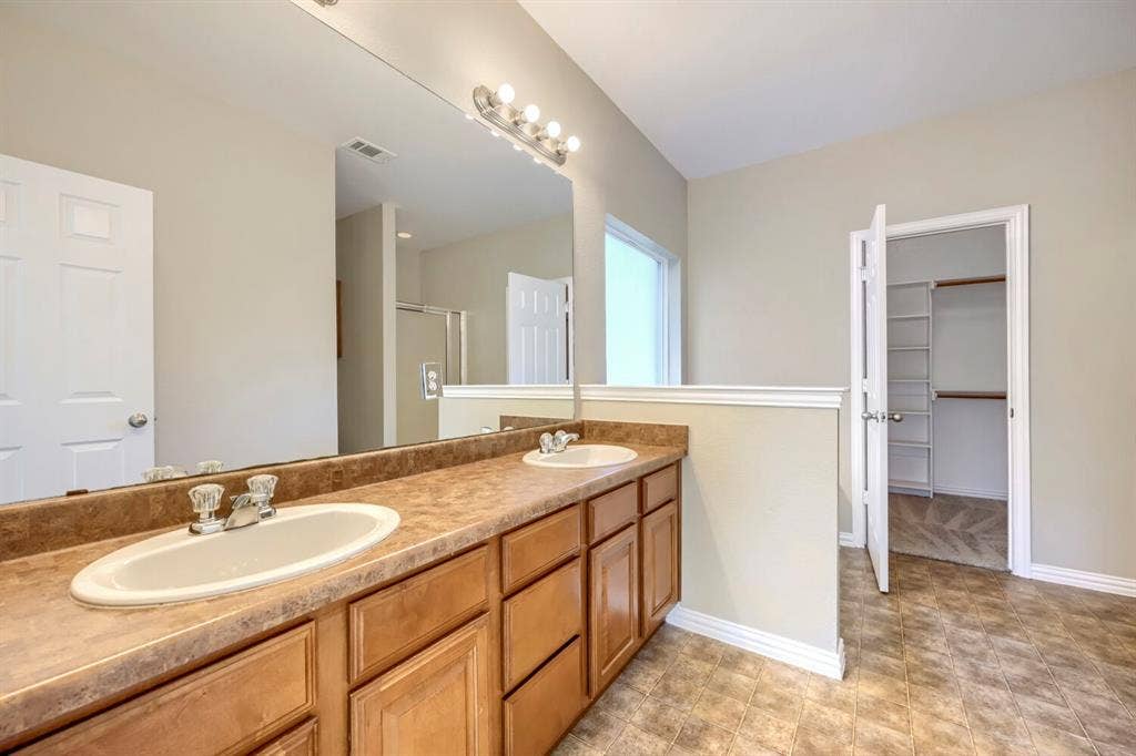 Dual vanity with integrated sinks, wood-finish cabinetry, and a full-width mirror