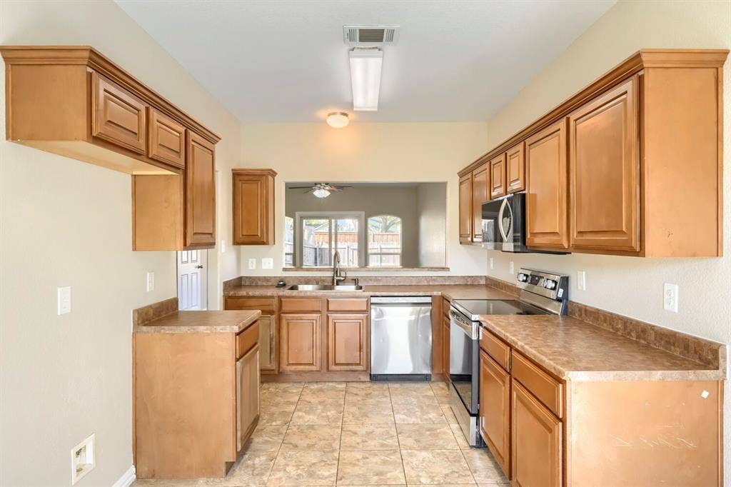 Kitchen featuring extensive cabinetry, laminate countertops, a stainless steel dishwasher, an electric range, and an over-range microwave