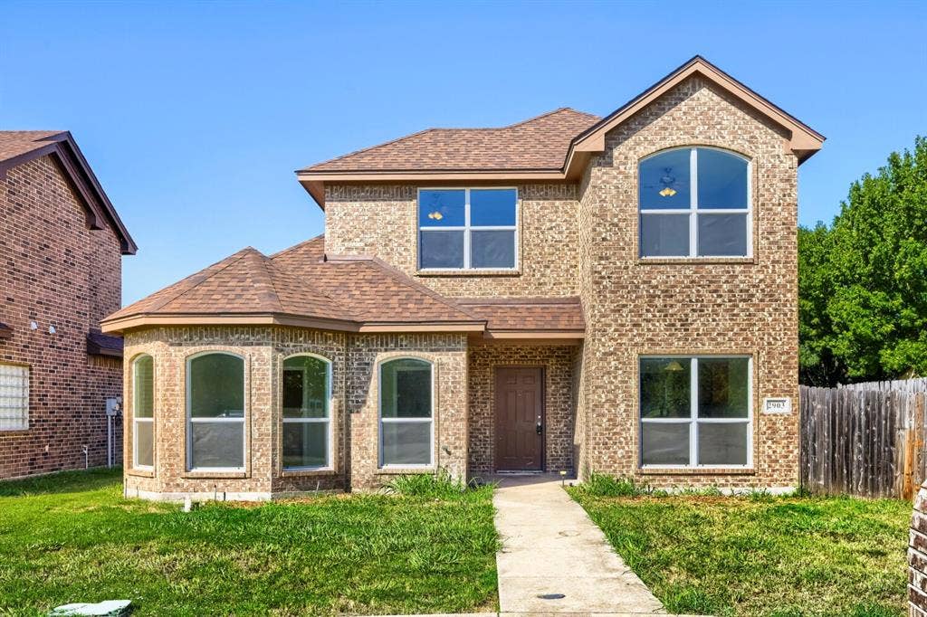 Brick exterior with an arched window, a bay window, and a brown front door