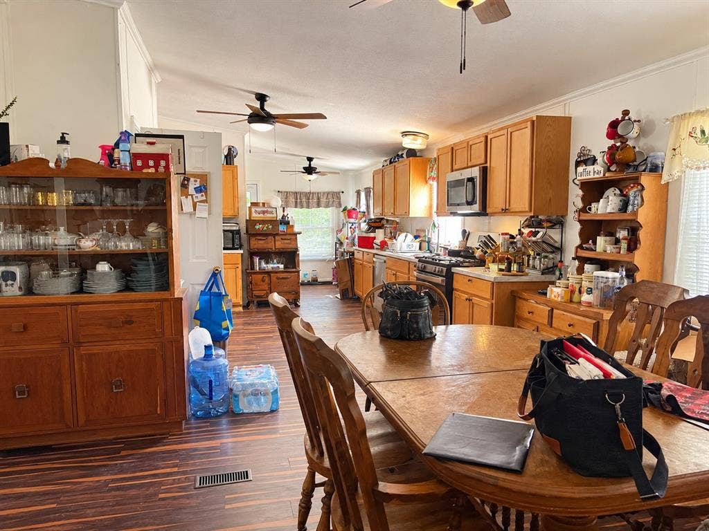 Expansive kitchen with wood-finish flooring, light wood cabinetry, stainless steel appliances, and ceiling fans