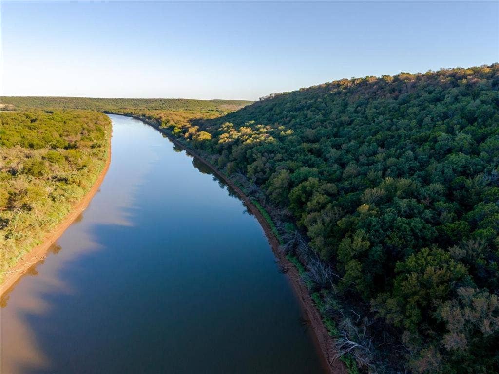 Riverfront property featuring a clear waterway and extensive tree coverage