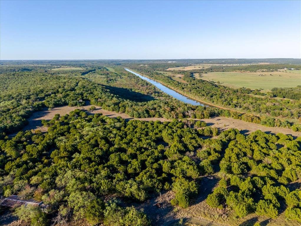 Expansive undeveloped land featuring a linear waterway and dense tree coverage