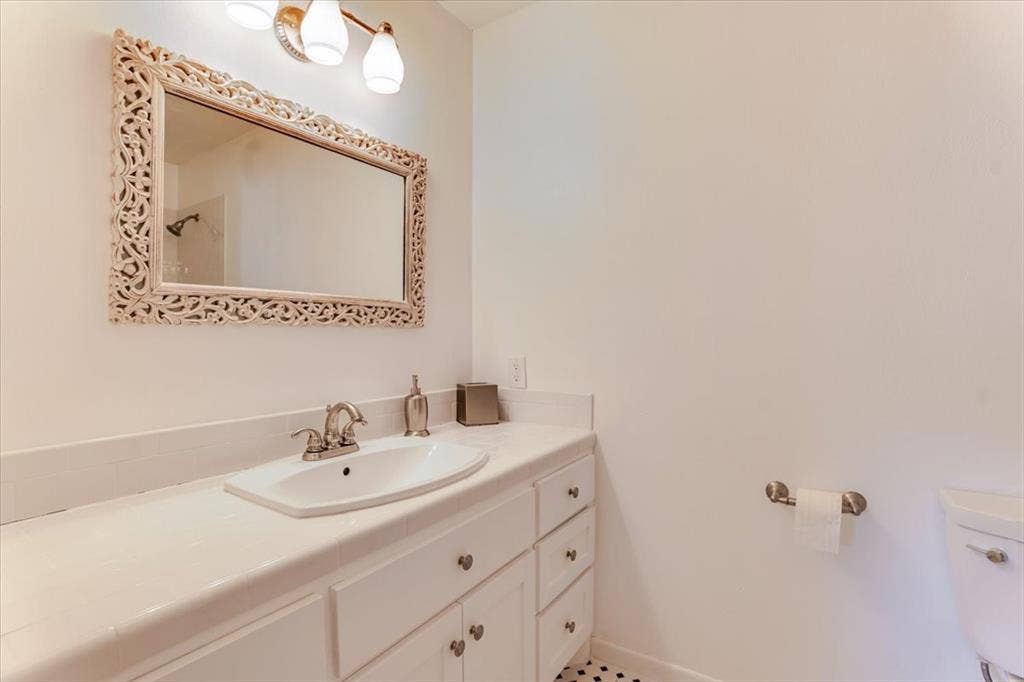 Vanity with an integrated sink, brushed nickel faucet, and a decorative carved mirror