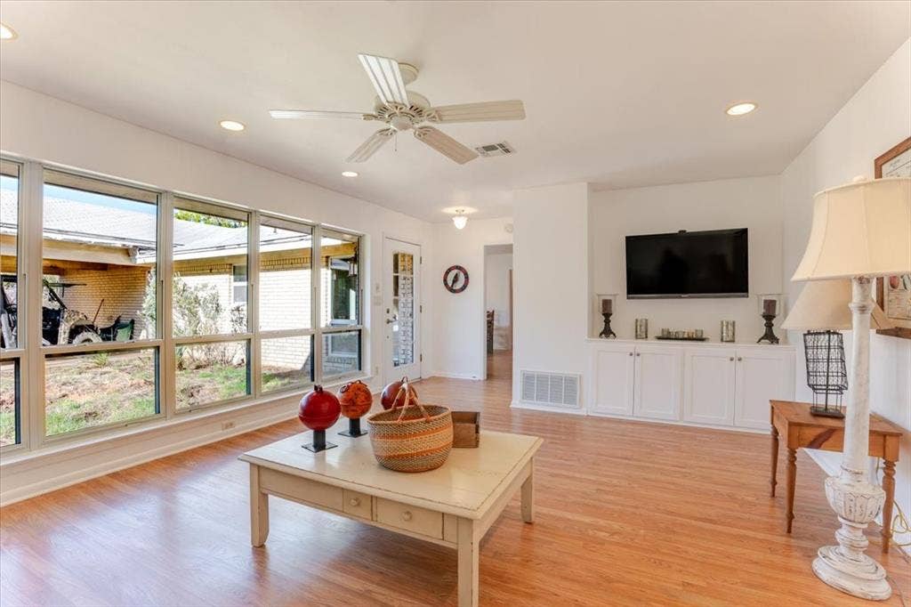 Wood-finish flooring, white built-in cabinetry, recessed lighting, and a ceiling fan with light fixture