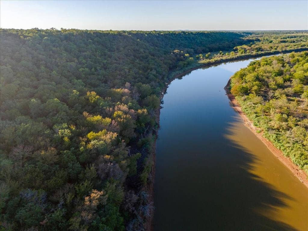 Expansive river frontage bordered by dense, mature tree lines and natural terrain