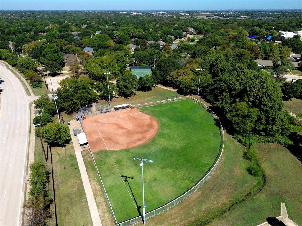 Recreational area featuring a baseball diamond with a grass outfield and dirt infield, spectator seating, and perimeter fencing