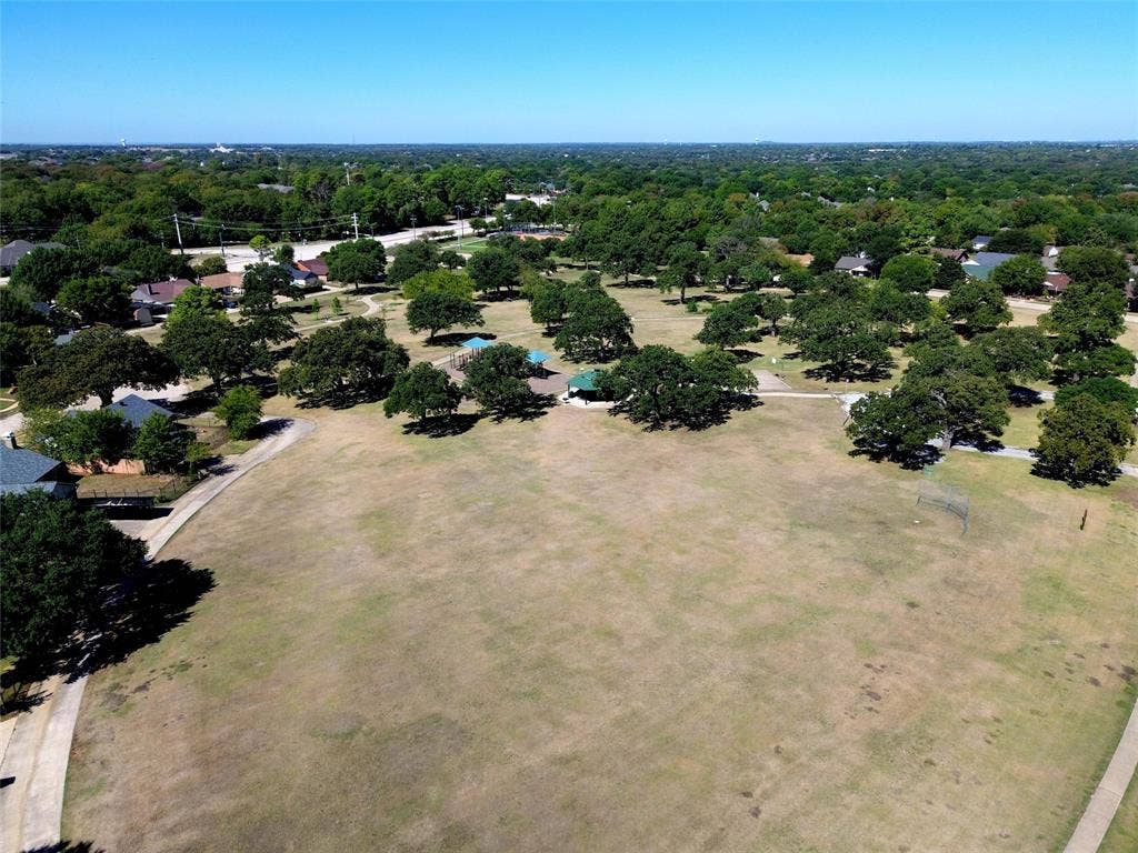 Expansive park setting featuring mature trees, paved pathways, and recreational areas