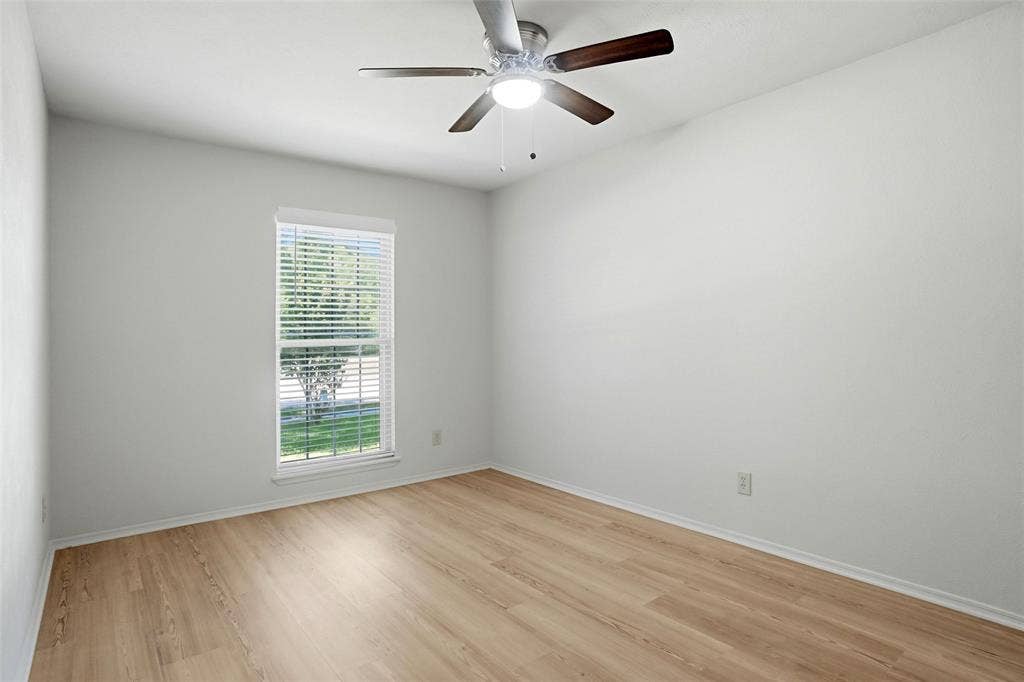 Recessed window with blinds, wood-finish flooring, and a ceiling fan with light fixture