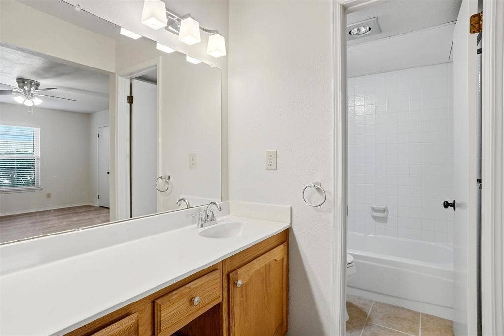 Bathroom vanity with a single sink, light wood-finish cabinetry, and a full-width mirror
