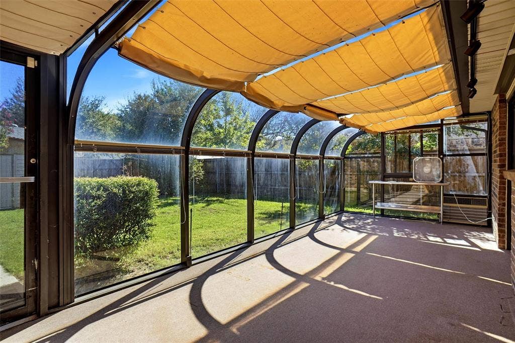 Arched glass enclosure with retractable fabric shades, brick exterior wall, and concrete flooring