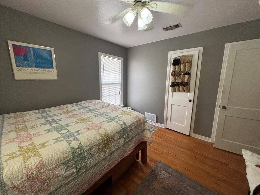 Hardwood flooring, painted walls, ceiling fan with light fixture, white trim, and white paneled doors
