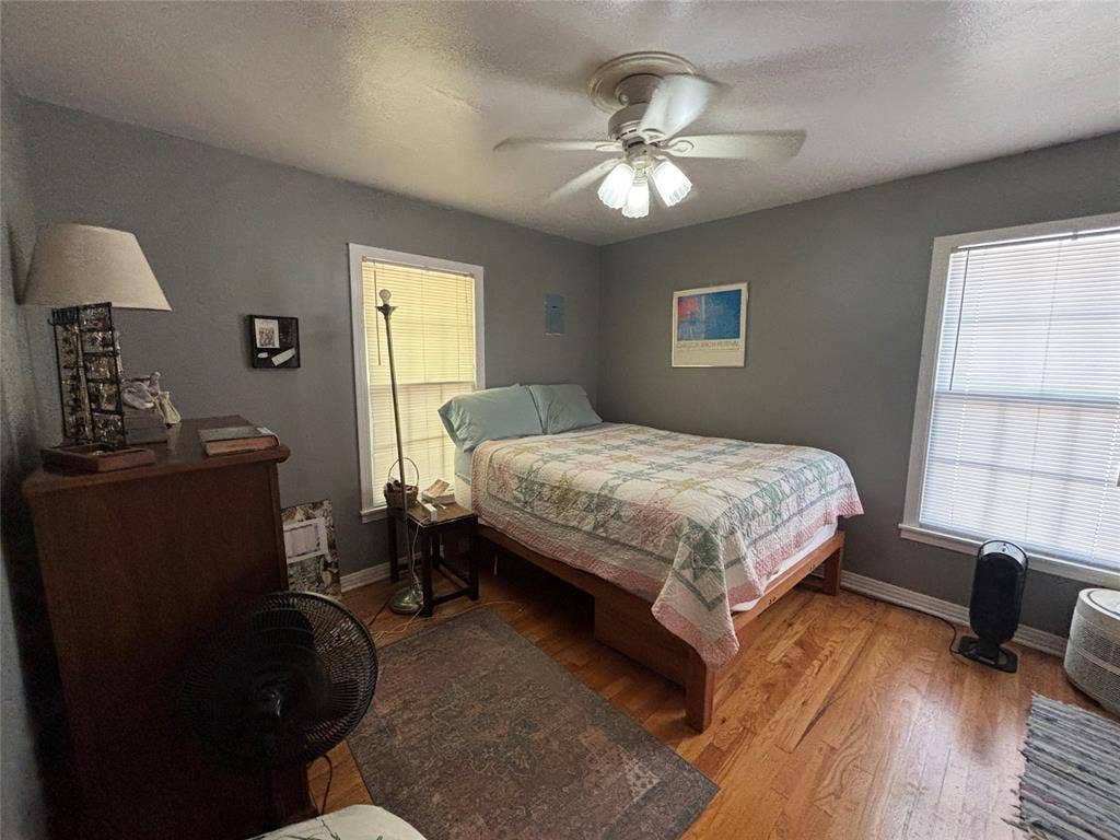 Hardwood flooring with a ceiling fan light fixture and multiple windows
