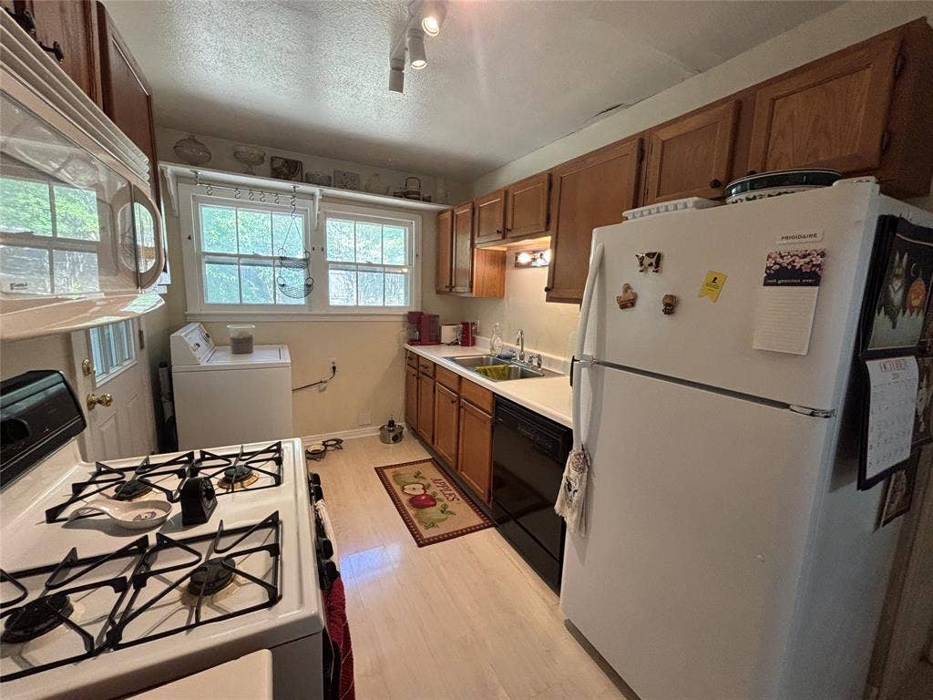 Full kitchen featuring wood-finish cabinetry, light-toned flooring, and a white gas range