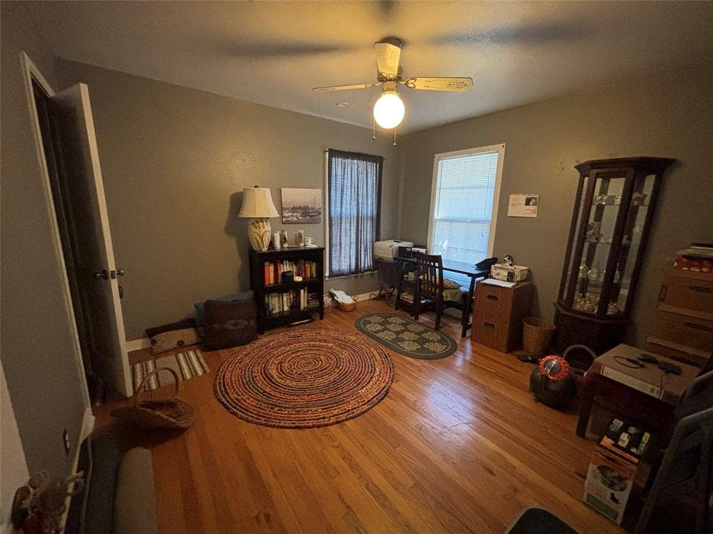 Hardwood flooring, painted walls, ceiling fan with integrated lighting, and a window for natural light