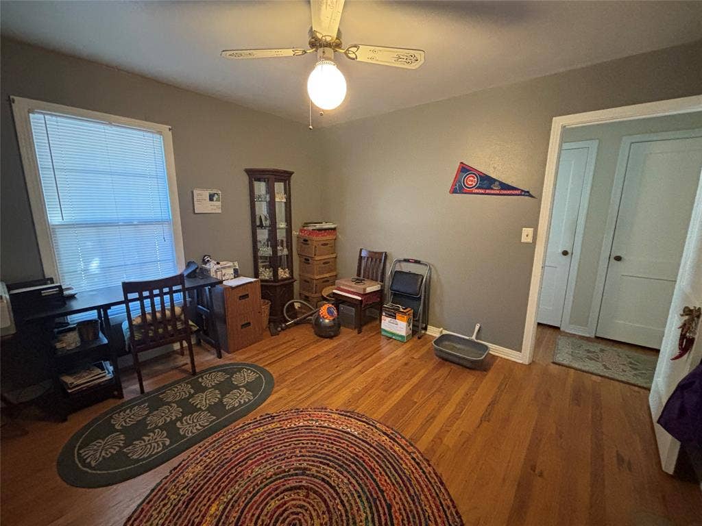 Hardwood flooring, painted walls, ceiling fan with light fixture, window with blinds, and white trim