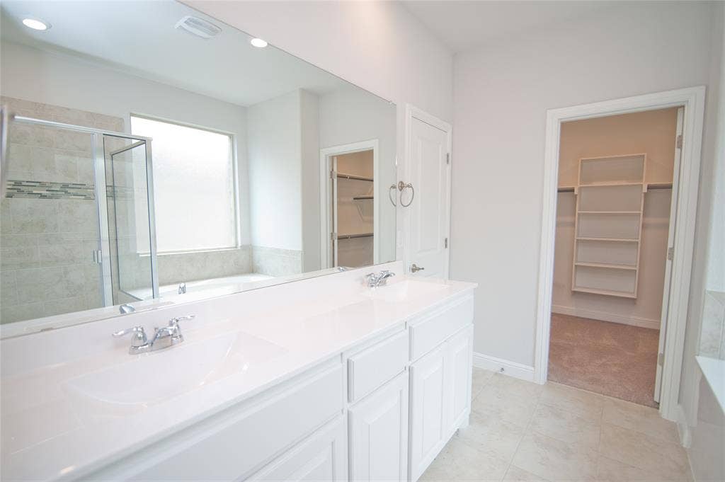 1021 Gillespie Drive, Fort Worth, TX 76247 Dual vanity with white cabinetry, polished chrome fixtures, and a large wall mirror
