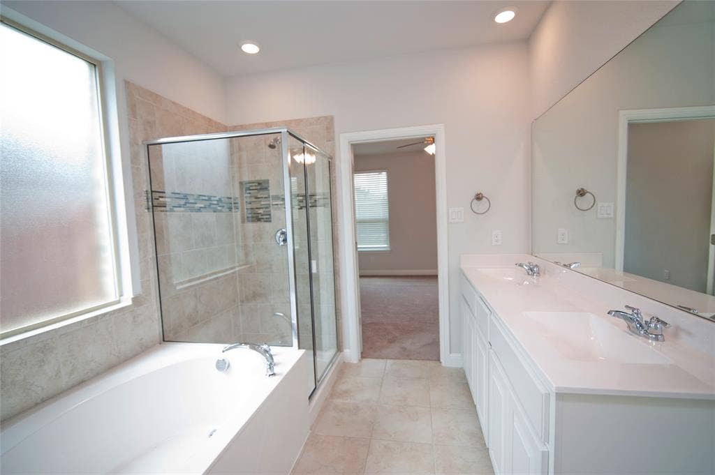 1021 Gillespie Drive, Fort Worth, TX 76247 Double vanity with undermount sinks, a built-in tub, a glass-enclosed shower, tile flooring, and recessed lighting