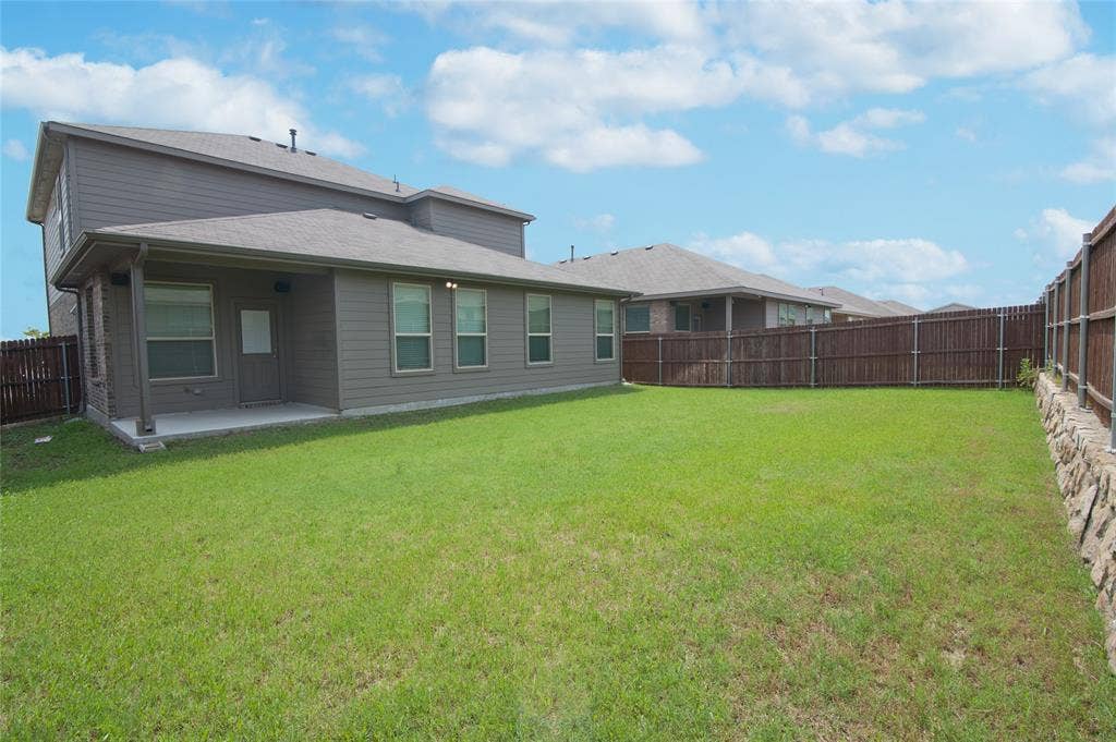 1021 Gillespie Drive, Fort Worth, TX 76247 Expansive lawn with a wooden privacy fence, a covered patio, and multiple windows
