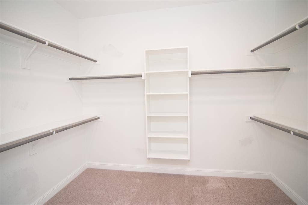 1021 Gillespie Drive, Fort Worth, TX 76247 White walls, built-in shelving unit, hanging rods, wall-mounted shelving, and carpet flooring