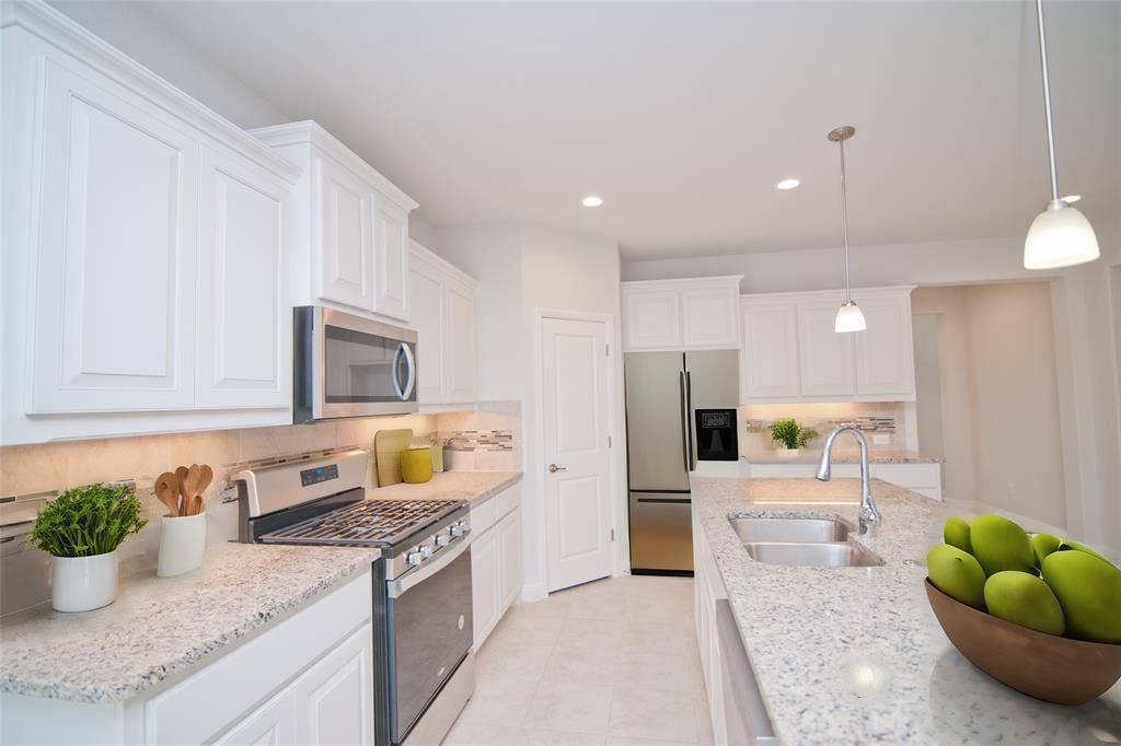 1021 Gillespie Drive, Fort Worth, TX 76247 White cabinetry with crown molding, stainless steel appliances, granite countertops, tile backsplash, and recessed lighting