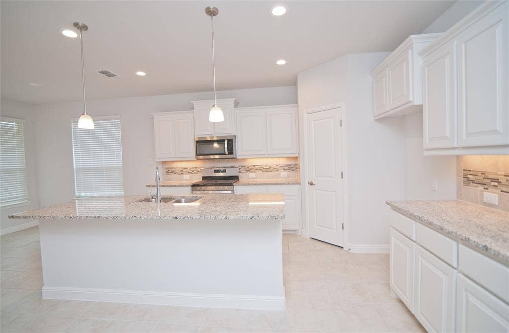 1021 Gillespie Drive, Fort Worth, TX 76247 Kitchen featuring a large island with sink, white shaker-style cabinetry, light-toned countertops, tile backsplash, and stainless steel appliances