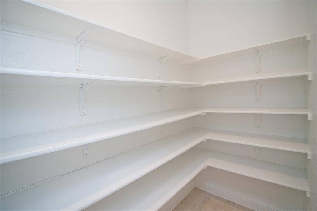 1021 Gillespie Drive, Fort Worth, TX 76247 Extensive corner pantry with multiple white shelves and tile flooring