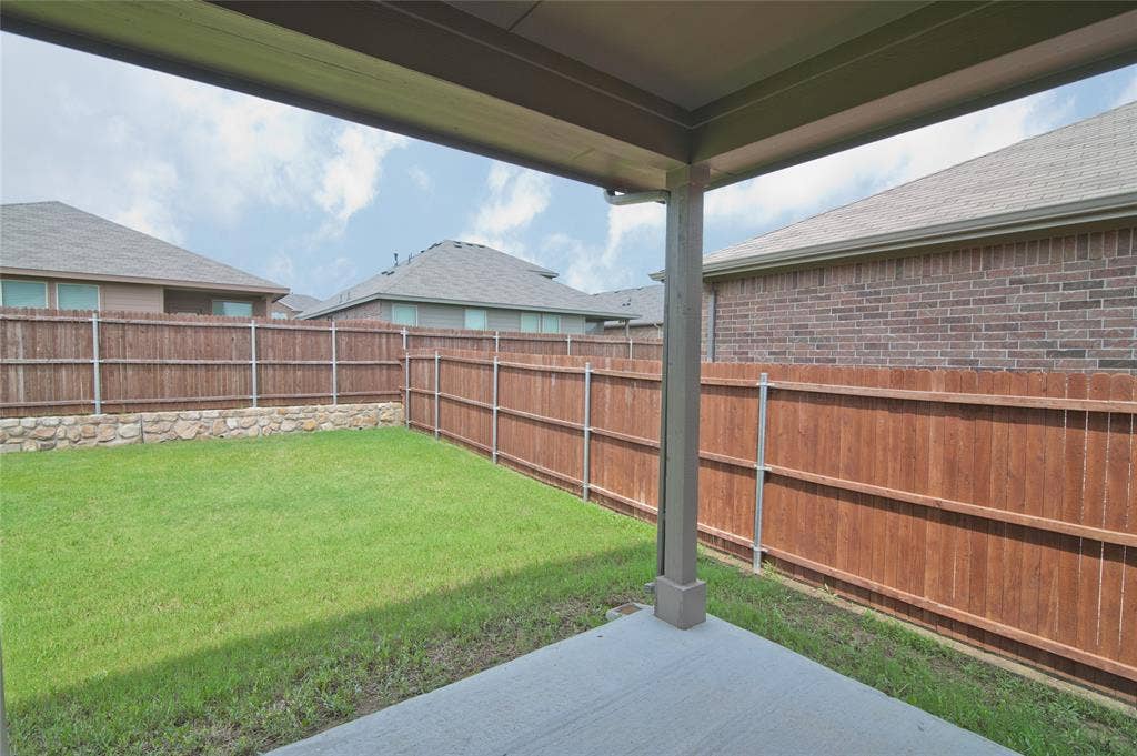 1021 Gillespie Drive, Fort Worth, TX 76247 Covered patio with concrete flooring, private wood fencing, and a stone retaining wall