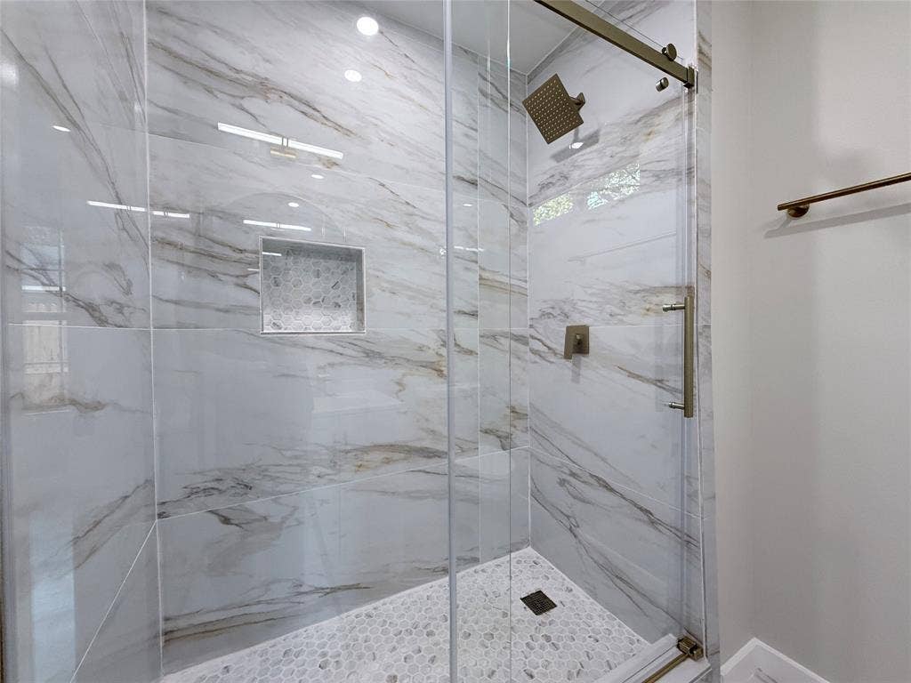 2538 Hooper Street, Dallas, TX 75215 Glass-enclosed shower with large format marble-look tile walls, a built-in niche with mosaic tile, and a pebble-tile shower floor