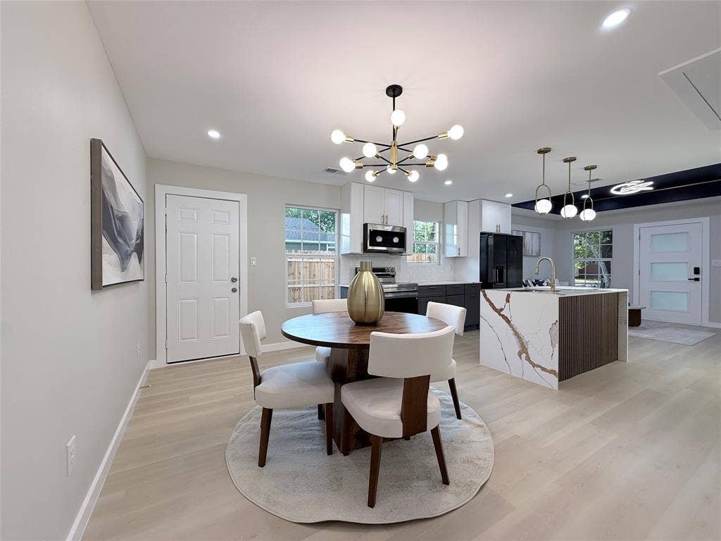 2538 Hooper Street, Dallas, TX 75215 Open-concept living space featuring wood-finish flooring, a modern kitchen island with an integrated sink, and contemporary light fixtures