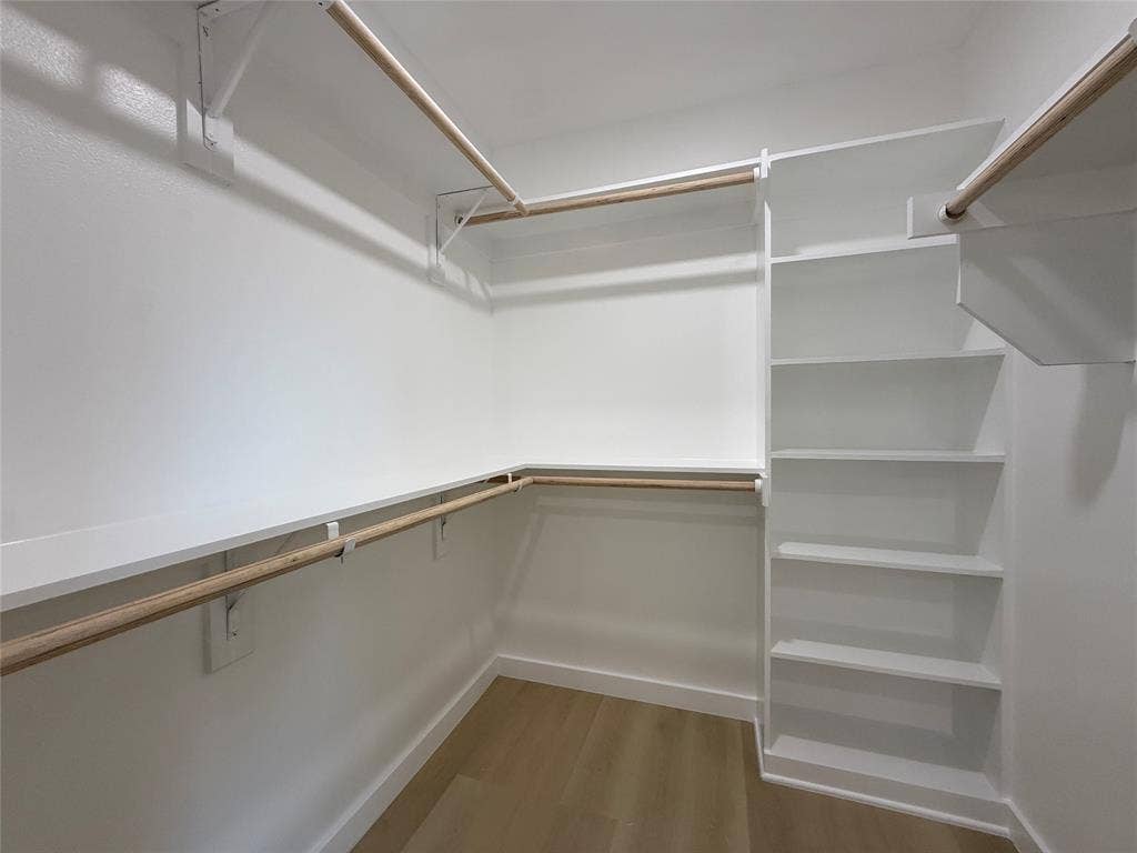 2538 Hooper Street, Dallas, TX 75215 Walk-in closet with multiple hanging rods, built-in shelving, and wood-finish flooring