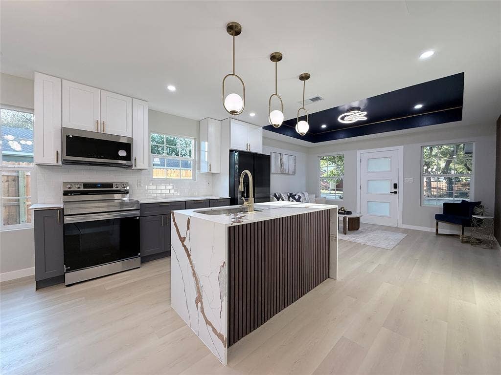 2538 Hooper Street, Dallas, TX 75215 Kitchen featuring a waterfall island with stone countertop, stainless steel appliances, and two-tone cabinetry