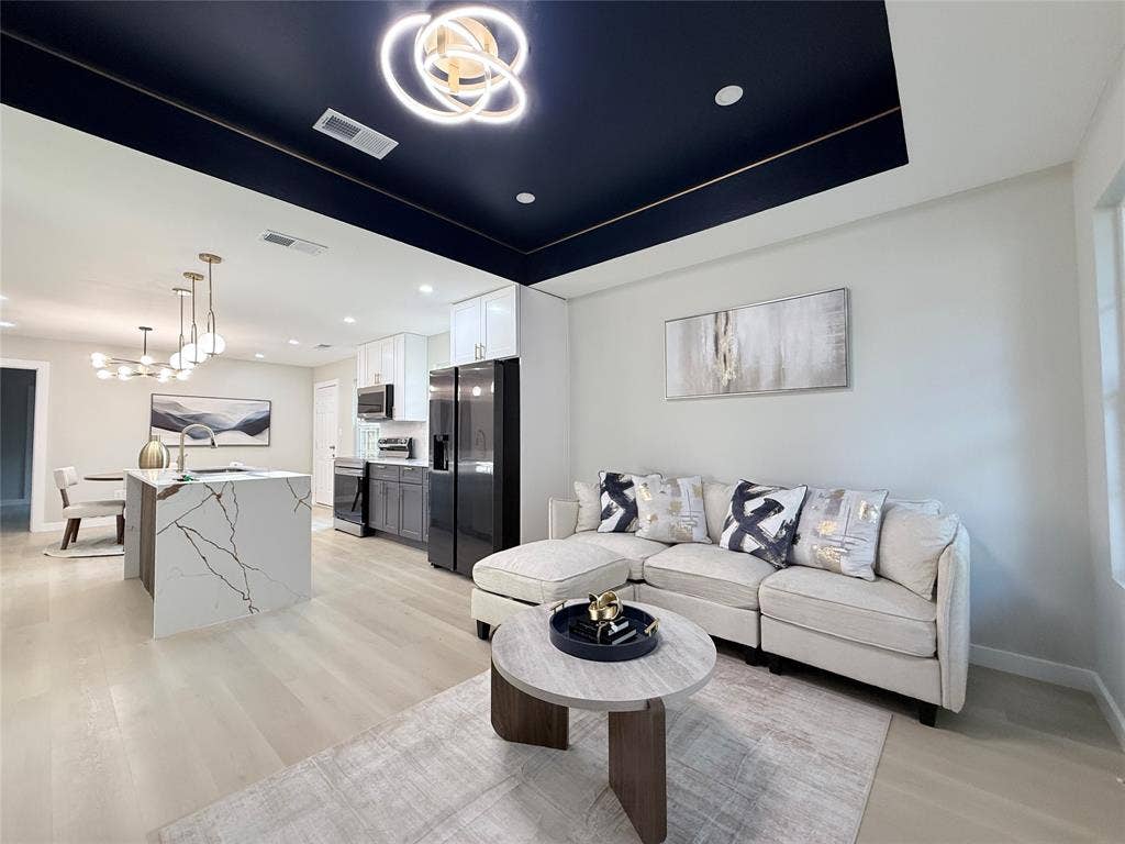2538 Hooper Street, Dallas, TX 75215 Open-concept living area with light wood-finish flooring, a contemporary ceiling light fixture, and a kitchen island featuring a waterfall countertop