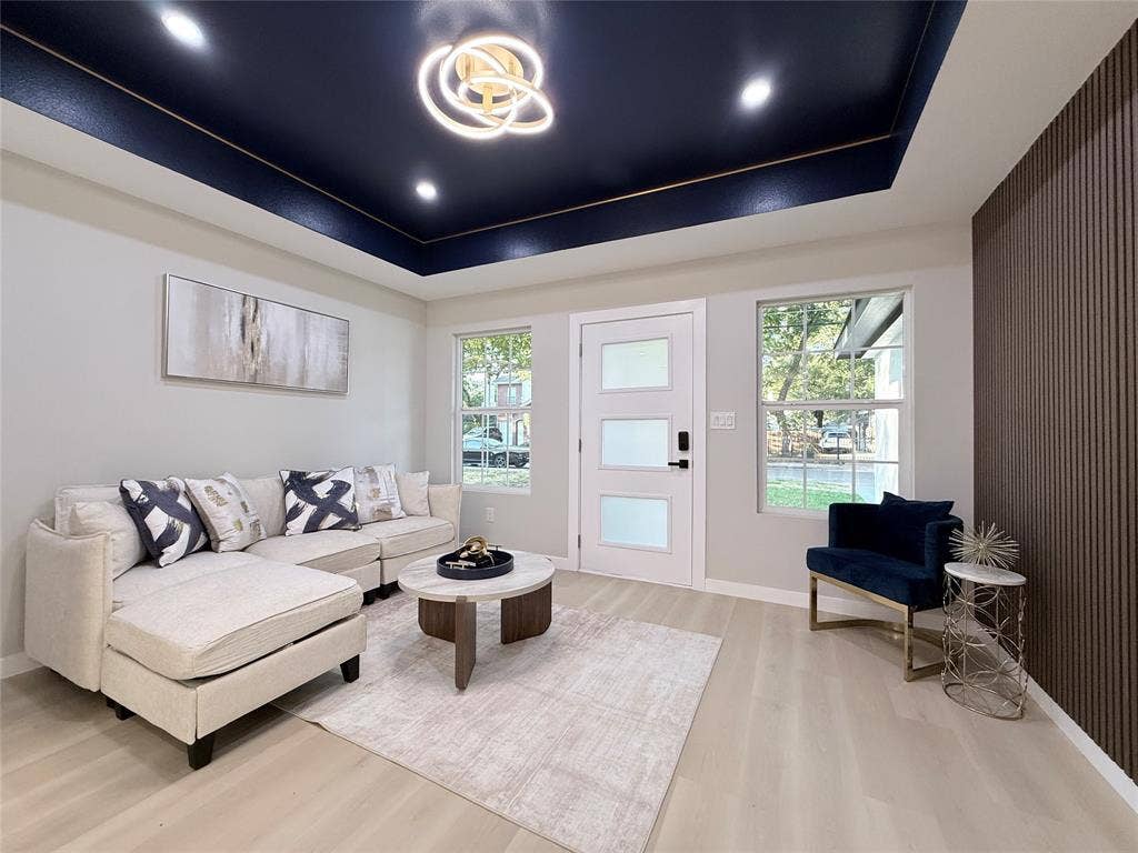 2538 Hooper Street, Dallas, TX 75215 Recessed ceiling with a dark accent color, contemporary chandelier, wood-finish flooring, white entry door with frosted panels, and a textured accent wall