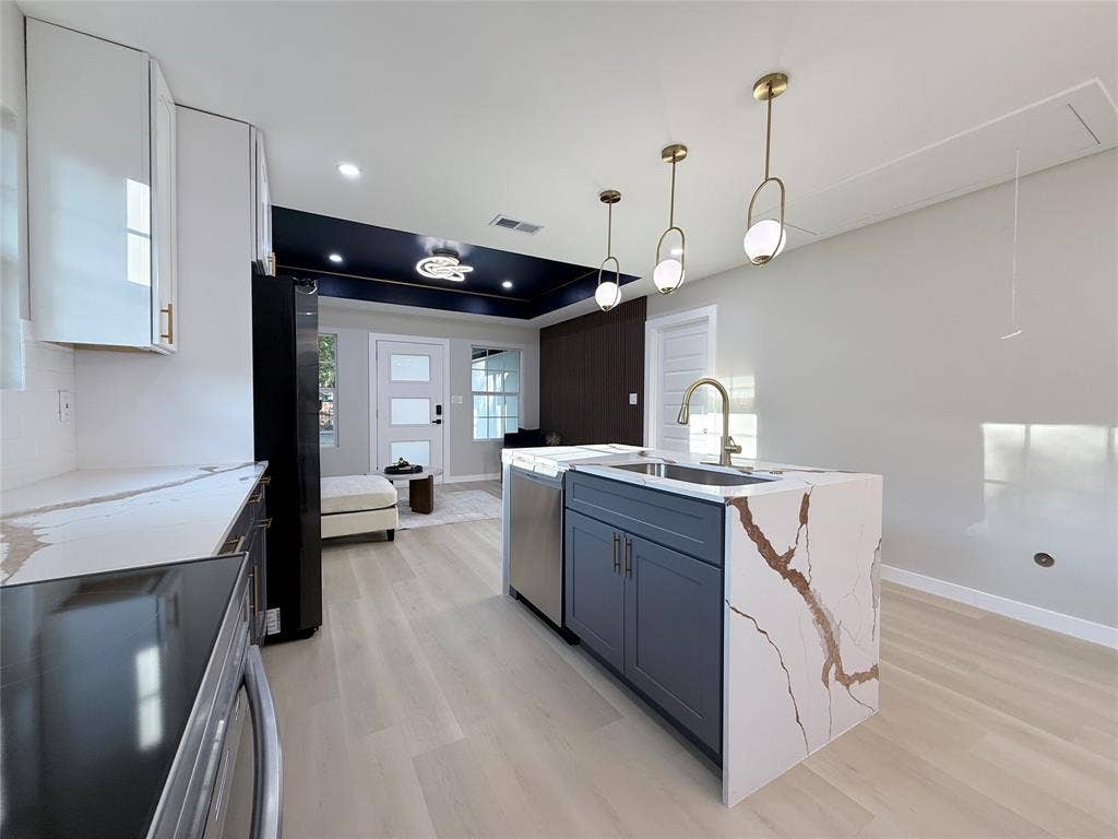 2538 Hooper Street, Dallas, TX 75215 Kitchen island with a waterfall-edge countertop, undermount sink, and brass-finish faucet