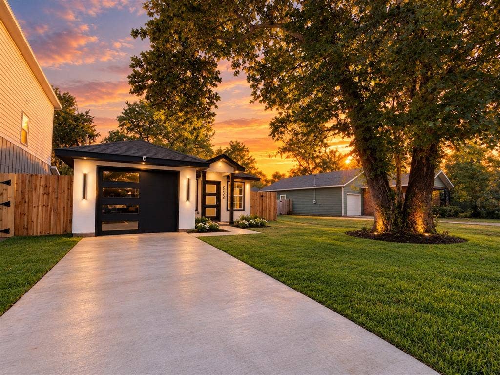 2538 Hooper Street, Dallas, TX 75215 Modern exterior with a black garage door featuring glass panels, vertical exterior lighting, and a dark asphalt shingle roof