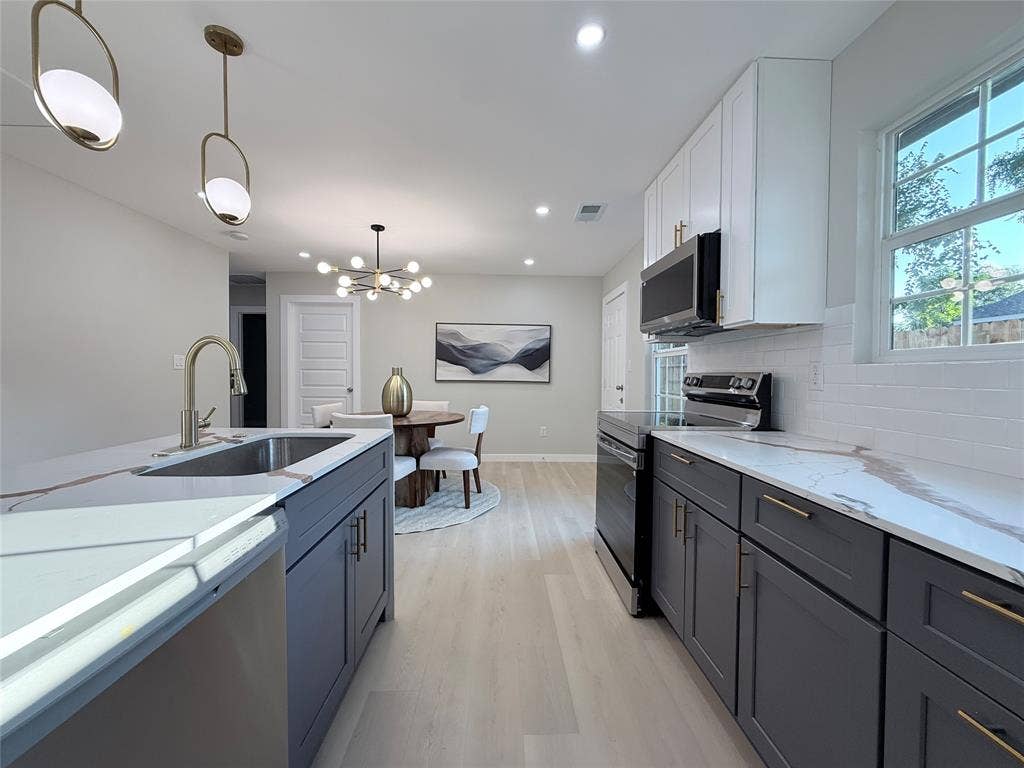 2538 Hooper Street, Dallas, TX 75215 Contemporary kitchen featuring light wood-finish flooring, white subway tile backsplash, and two-tone cabinetry with gold-tone hardware
