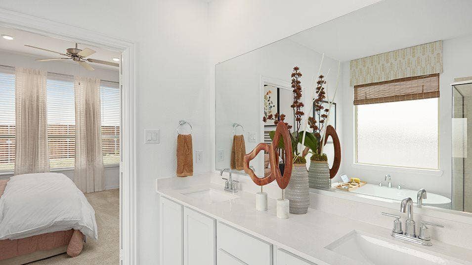 Dual vanity with integrated sinks and chrome fixtures, large mirror, freestanding bathtub, and a window with privacy glass