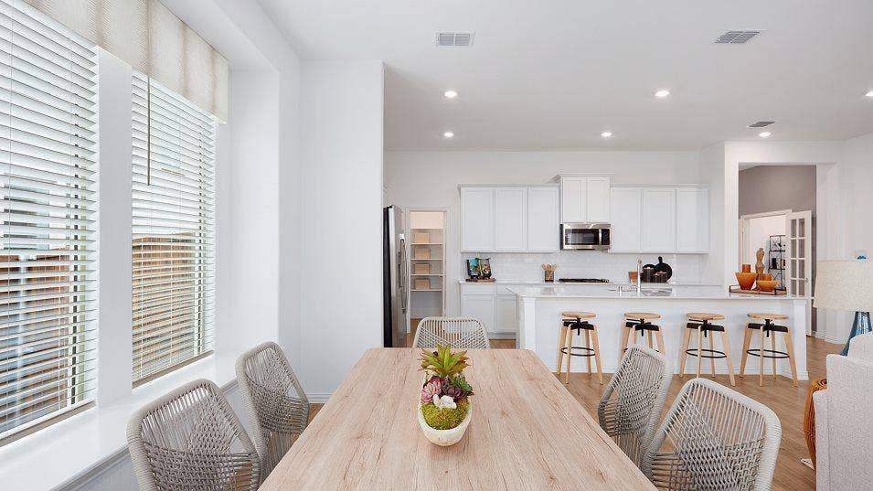 White kitchen cabinetry with stainless steel appliances, a center island with seating, a tile backsplash, and recessed lighting