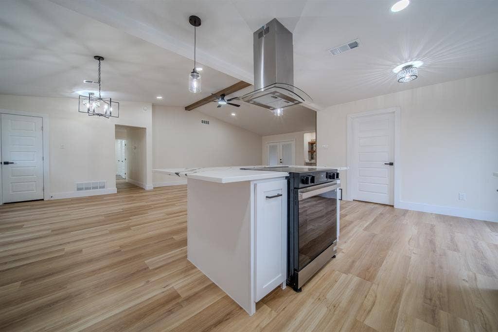 Open-concept kitchen featuring an island, stainless steel range with range hood, and wood-finish flooring