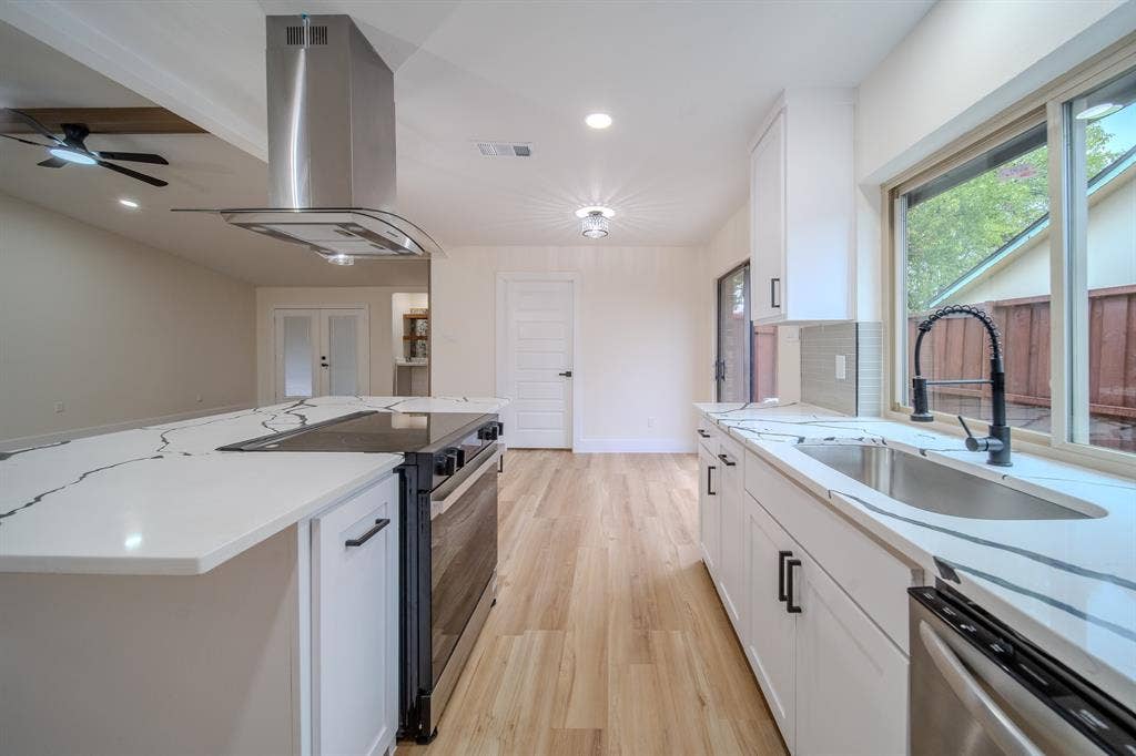 Contemporary kitchen featuring white cabinetry, quartz countertops, stainless steel appliances, wood-finish flooring, and recessed lighting