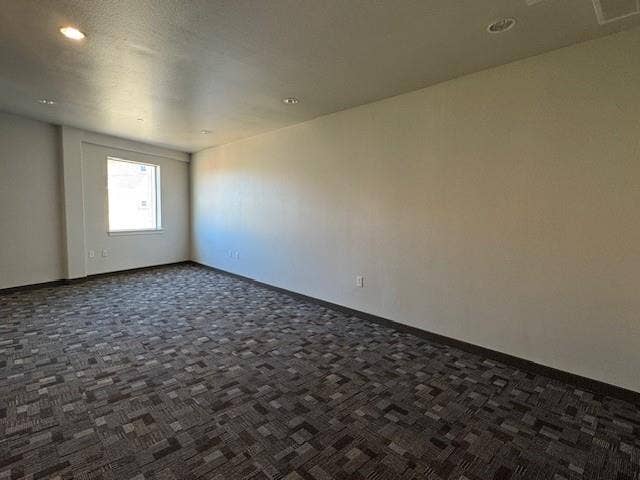 Recessed lighting, neutral wall finishes, patterned carpet flooring, and a window for natural light