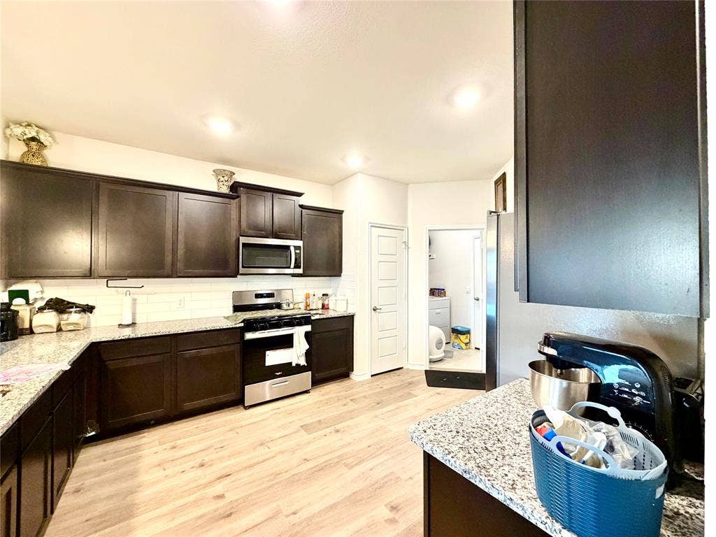 Kitchen featuring dark wood-finish cabinetry, light-toned wood-finish flooring, and white subway tile backsplash