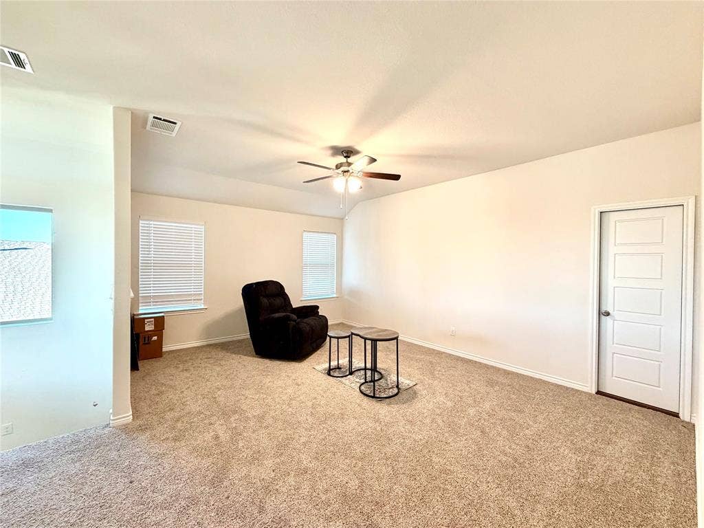 Vaulted ceiling with a ceiling fan, carpeted flooring, multiple windows with blinds, and paneled interior doors