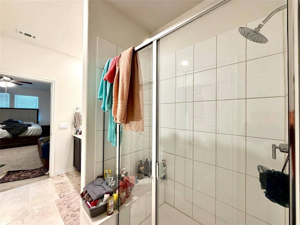 Glass-enclosed shower with white tiled walls and a rain showerhead