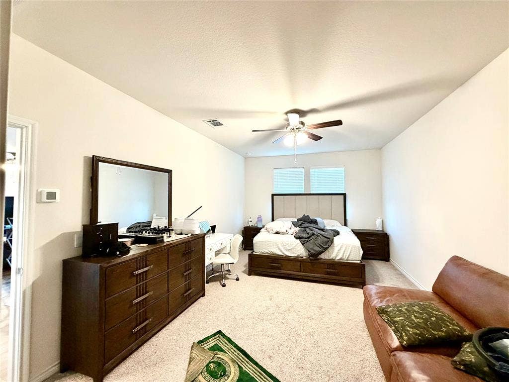 Carpeted flooring, white walls, and a ceiling fan with light fixture