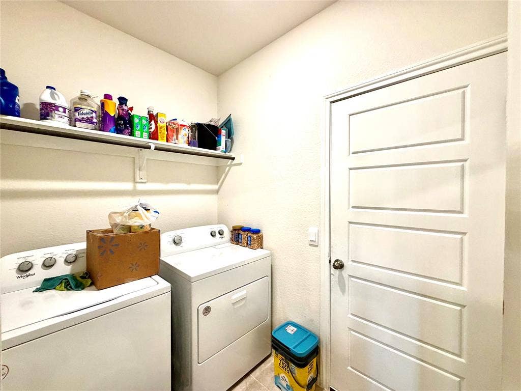 Laundry area featuring an overhead shelf, a white paneled door, and neutral wall tones
