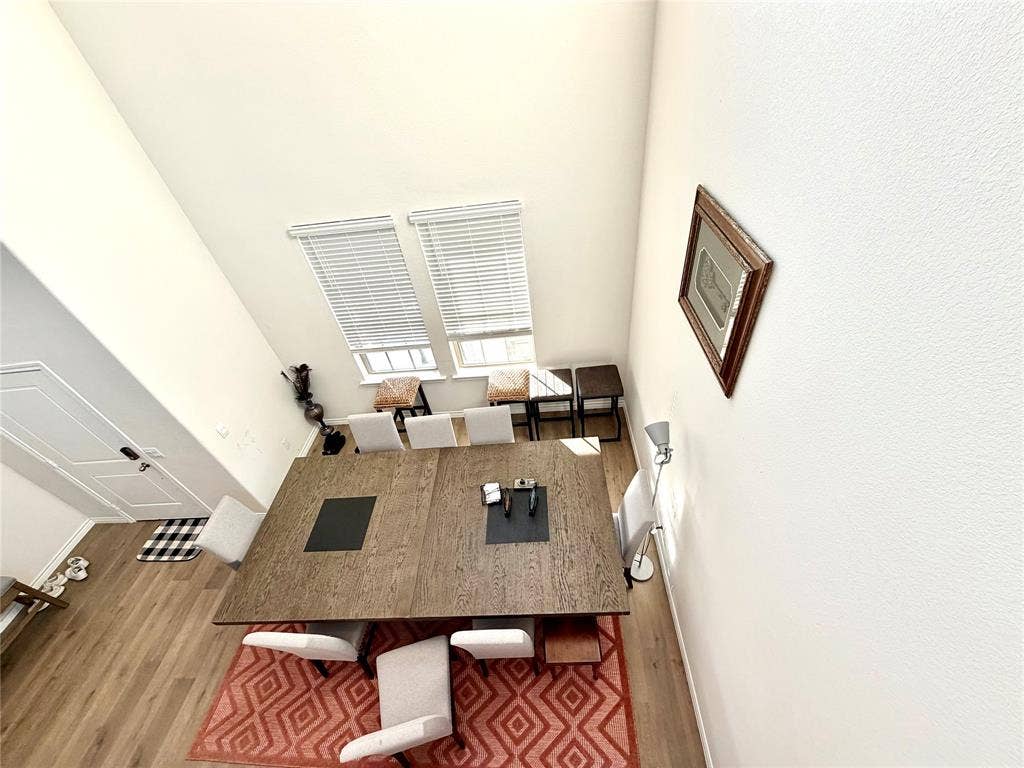Vaulted ceiling with dual windows, wood-finish flooring, and white interior doors