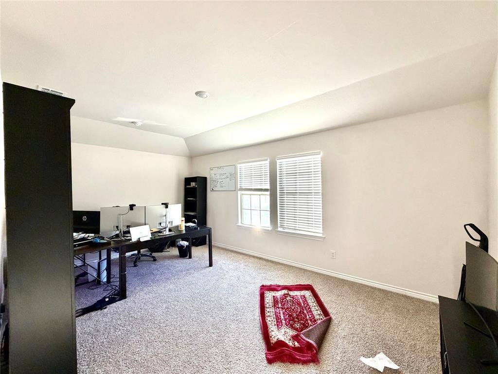 Carpeted room featuring multiple windows with blinds and a vaulted ceiling